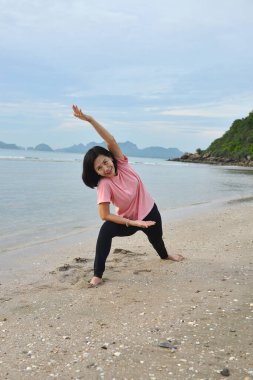 sağlıklı bir kadın gün doğumunda plajda yoga yapıyor.