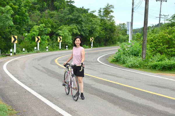 Asian  woman with bicycle on a forest road