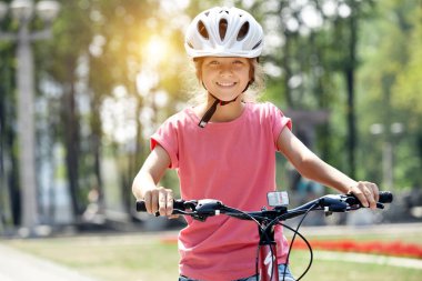 Kask ve Şehir Parkı içinde bisiklet ile kız. Kamera ve gülümsüyor görünüyor.
