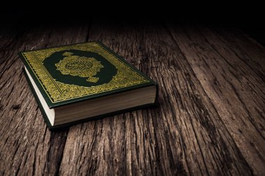 Koran - holy book of Muslims ( public item of all muslims ) on the table , still life  . clipart