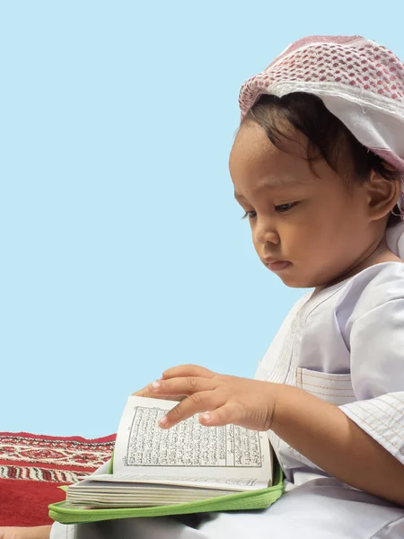 Muslimischer Junge in einem Kleid, der den Koran liest, isolierter Hintergrund — Stockfoto