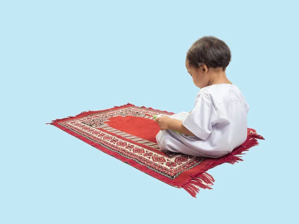Muslimischer Junge in einem Kleid, der den Koran liest, isolierter Hintergrund — Stockfoto