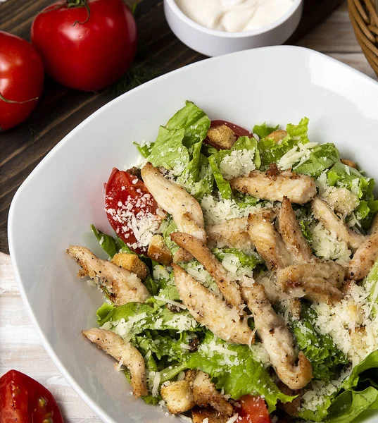 Chicken parmesan caesar salad with lettuce, cherry tomatoes .