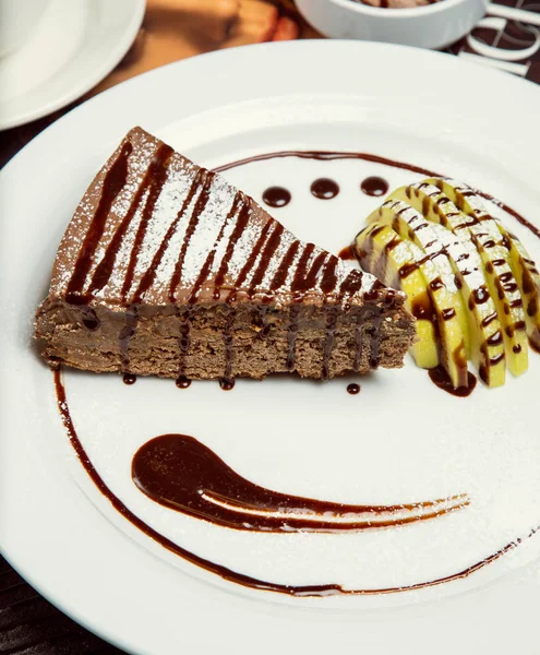 Chocolate apple pie slice with choco sauce and apple slices.