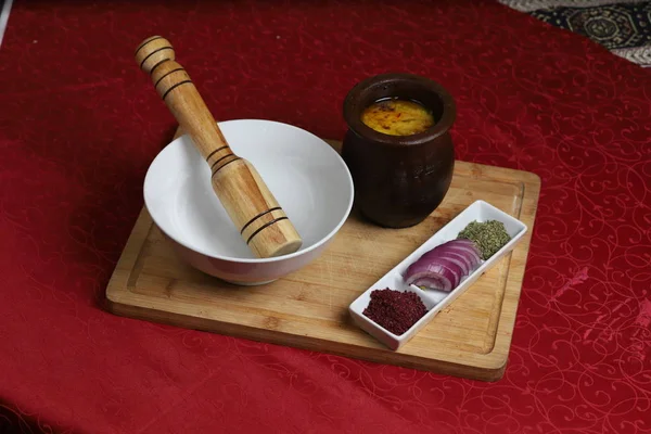 White bowl and wooden stick to prepare hot chili sauce with herbs and onion. — 스톡 사진