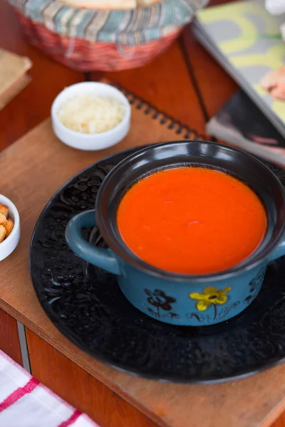 Rajčatová polévka v hrnci s nakrájeným parmazánem a suchými pečivo. — Stock fotografie
