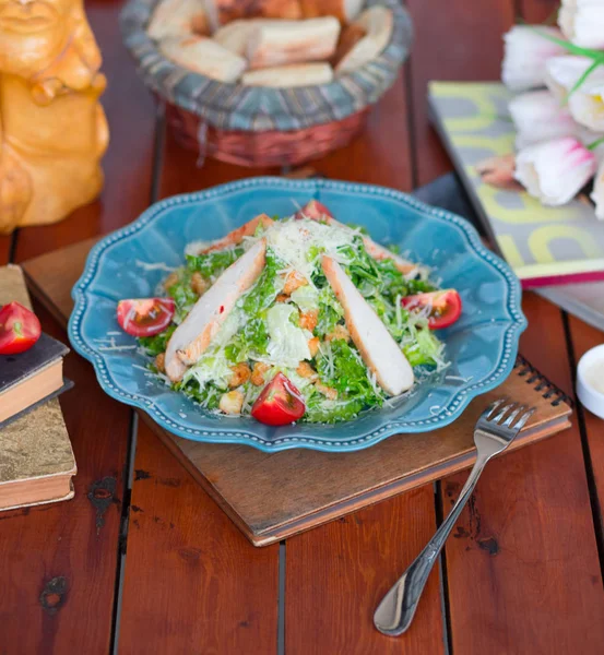 Chicken caesar salad with chopped parmesan cheese fresh lettuce and tomatoes, crackers in blue plate. — Stock Photo, Image