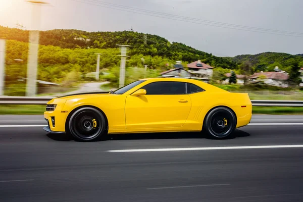 Carro esporte sedan amarelo com corda preta sobre ele, vista lateral na estrada . — Fotografia de Stock