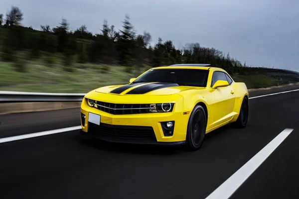 道路上の高速で運転するその上に黒い文字列を持つ黄色のセダンスポーツカー. — ストック写真