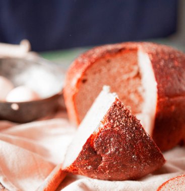 Üzerinde otlar, pizza dilimleri, rustik bir havlu etrafında yumurta ile bütün bir geleneksel yuvarlak ekmek yan görünümü, .