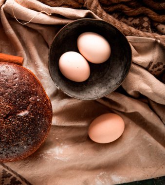 Tarçın sopa ile beyaz bir masa örtüsü üzerinde bütün ev yapımı sağlıklı ekmek, bir kase yumurta, üst görünümü.