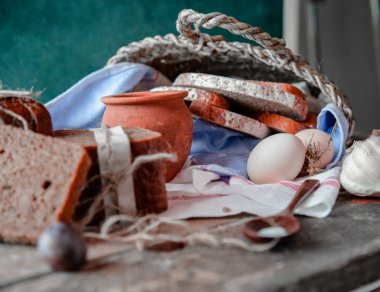 Sepet içinde sarılmış ekmek dilimleri ile, süt tenceresi ve erik dışında beyaz bir havlu, yumurta ve sarımsak etrafında. 