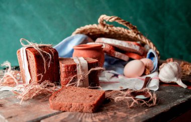 Yan görünüm sarılmış ekmek dilimleri, süt tenceresi, ahşap bir masa üzerinde sepet. 