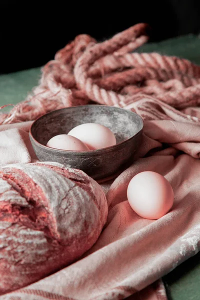 Ολόκληρο στρογγυλό ψωμί σε μια ρουστίκ πετσέτα κουζίνας με μπολ αυγών. — Φωτογραφία Αρχείου