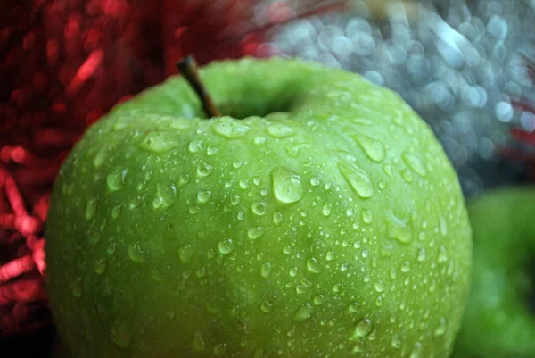 Ein einziger grüner Apfel mit Wassertropfen darauf — Stockfoto