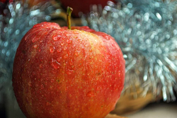 Ein einziger roter Apfel mit Wassertropfen darauf im festlichen Hintergrund — Stockfoto