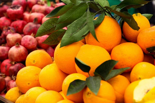 Gelbe Orangen mit roten Granatäpfeln auf dem Hintergrund — Stockfoto