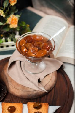 Ahşap bir tahtanın üzerinde cam bir kavanozda sarı erik konservesi