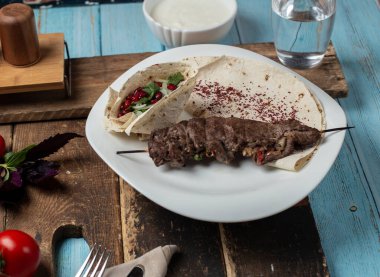 Ahşap bir tahtanın üzerinde lahanalı ekmek ile servis edilen et barbeküsü.