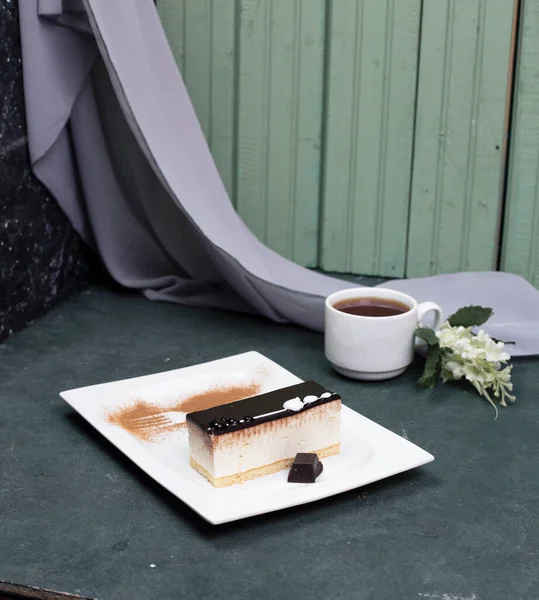 Una rebanada de pastel de queso de chocolate y una taza de té en la mesa azul — Foto de Stock