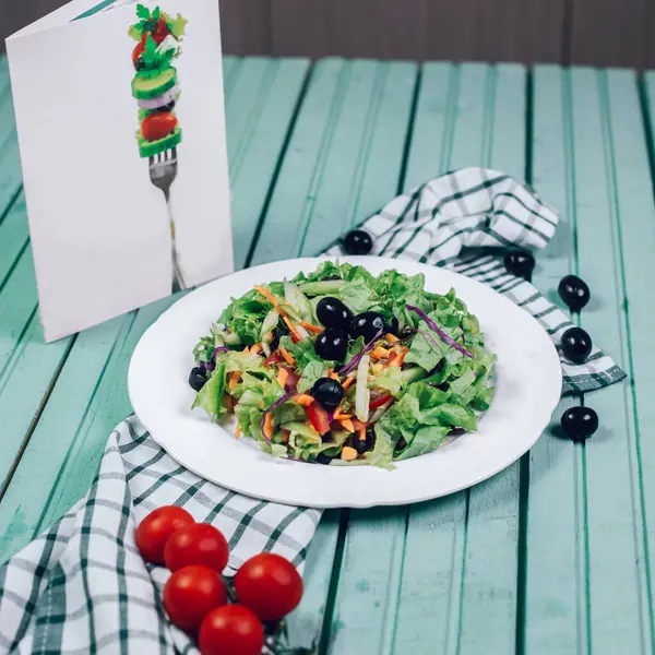 Зелений салат з подрібненим салатом і чорними оливками з помідорами навколо — стокове фото