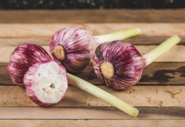 Tahta bir masada taze sarımsak eldiveni, bir tanesi kesilmiş.