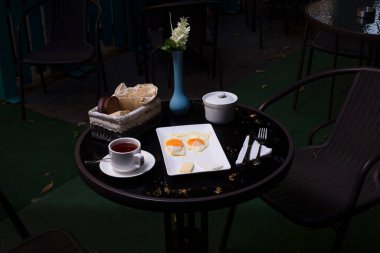 Kahvaltı tabağında kızarmış yumurta ve bir fincan çay ile servis edilir.