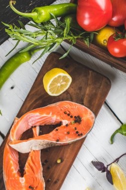 Limonlu, domatesli ve otlu iki dilim somon fileto.