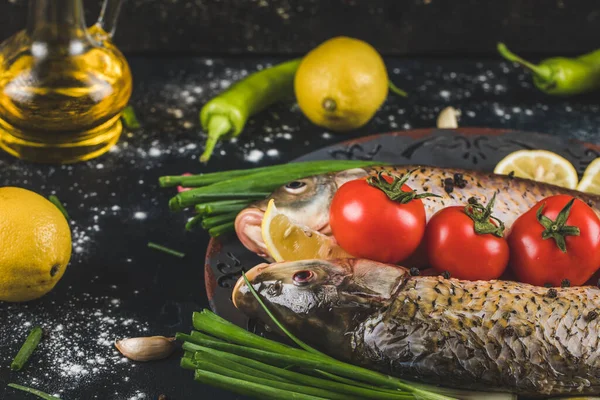 Сырая рыба готова к приготовлению с травами, специями, помидорами и лимоном в декоративном блюде — стоковое фото