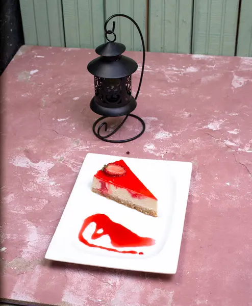 흰 접시에 딸기 소스를 곁들인 치즈 케이크 한 조각 — 스톡 사진