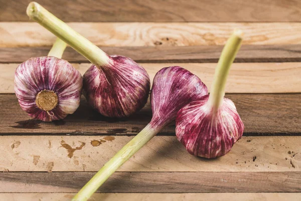 Petits gants à l'ail rose sur une table en bois, vue de dessus — Photo