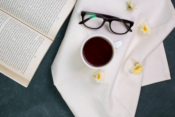 Une tasse de thé, des verres optiques et un livre sur une nappe blanche — Photo