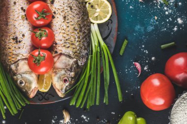 Limonlu balık, domates ve mavi masada doğranmış otlar.