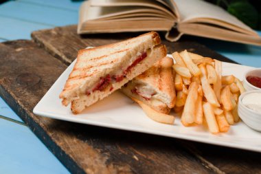 Tahtada kızarmış patatesle servis edilen kulüp sandviçleri.