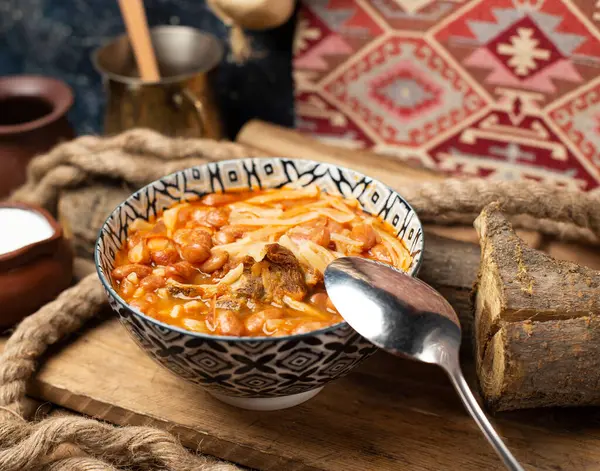 Frijoles caucásicos tradicionales con arroz y pasta en un tazón con una cuchara alrededor — Foto de Stock