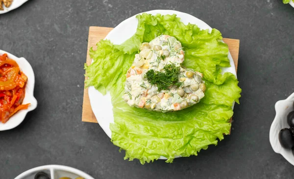 Russian stolichni salad in heart shape on a lettuce with minced drill on the top. top view — Stock Photo, Image