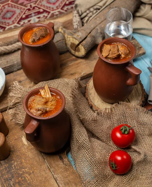 Piti caucasien en sauce avec de la viande dans une casserole avec des tomates autour — Photo