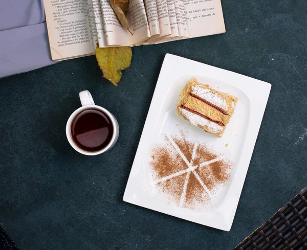 계피 파우더가 들어 있는 바닐라 케익 한 조각 과 백판에 담긴 차 한 잔, 맨 위에 보이는 것 — 스톡 사진