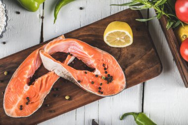 Tahtanın üzerinde sebzeli somon filetosu.