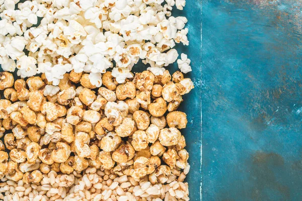 Popcorn , caramel corn and wheat corn snacks on blue backdrop