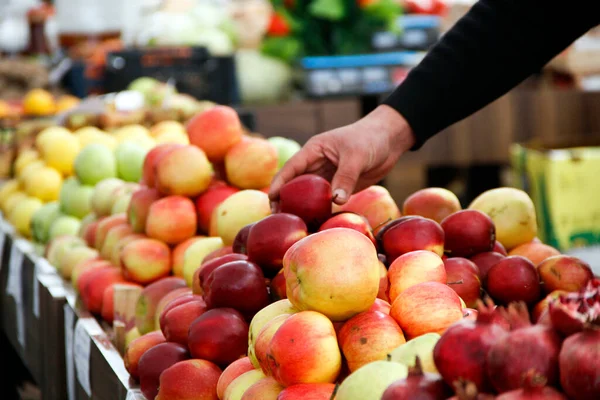 Mann holt rote Äpfel vom Gemüsestand — Stockfoto
