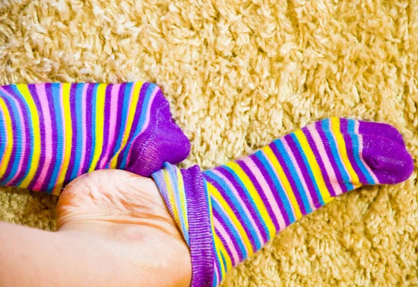 striped colored socks, legs on a soft mat