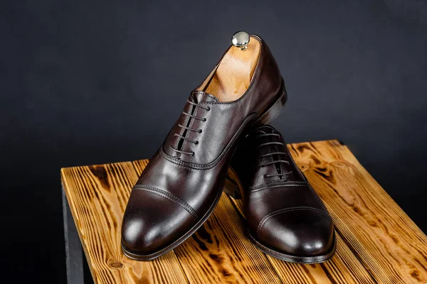 Sapatos castanhos de couro elegantes contra um fundo escuro . Imagem De Stock