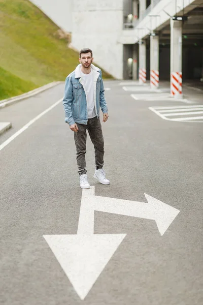 Killen i jeansjacka står på en tom gata Royaltyfria Stockbilder
