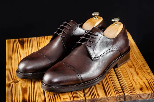 Sapatos castanhos de couro elegantes contra um fundo escuro . — Fotografia de Stock