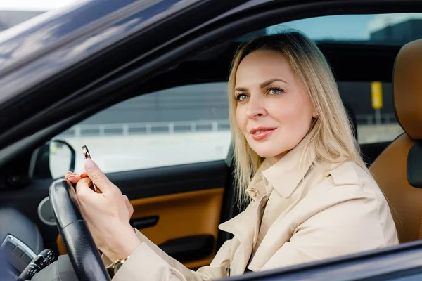 Kvinna som använder mobiltelefon och kör bil Stockfoto