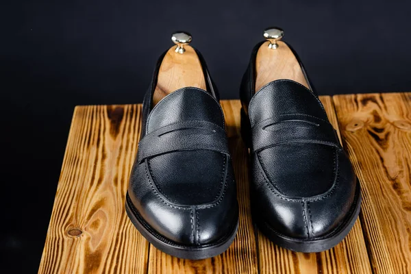 Mocassins pretos sobre fundo preto. sapatos em um suporte de madeira — Fotografia de Stock