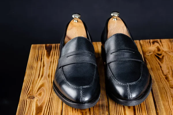 Mocassins pretos sobre fundo preto. sapatos em um suporte de madeira Fotografias De Stock Royalty-Free