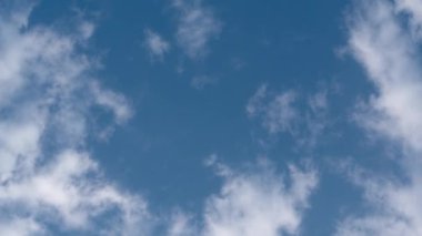 Mavi gökyüzünde beyaz bulutlar (alt manzara). Kabarık beyaz bulutlar mavi gökyüzü arka planında çaprazlama uçar, sanki başınızı kaldırmışsınız gibi. Zaman aşımı.