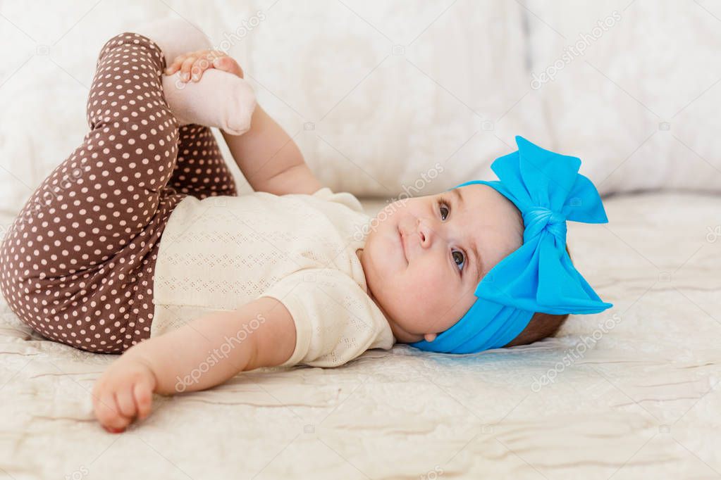 a little girl whose half a year, 6 months old, in cute body and skirt, with bright bow on a head. Sweet smiling Baby girl in studio